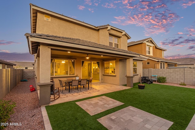 back of property with a fenced backyard, a lawn, a patio, and stucco siding