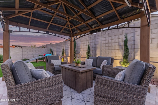 patio terrace at dusk with fence, a gazebo, and an outdoor hangout area