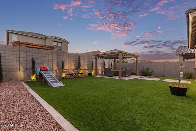 yard at dusk with a gazebo, a patio, and a fenced backyard