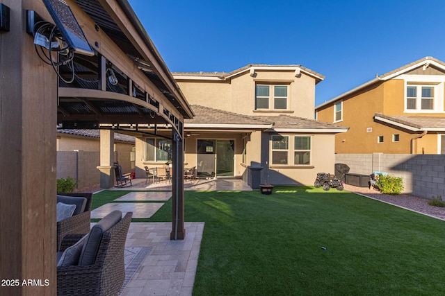 rear view of house with a yard, a patio area, a fenced backyard, and stucco siding