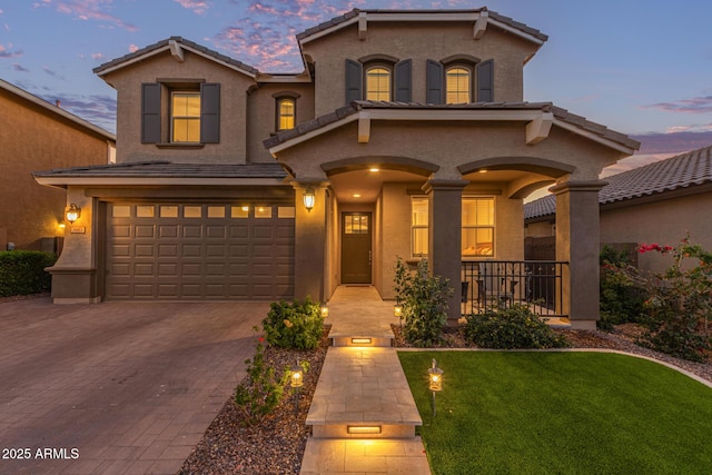 mediterranean / spanish home with a garage, a tiled roof, and stucco siding