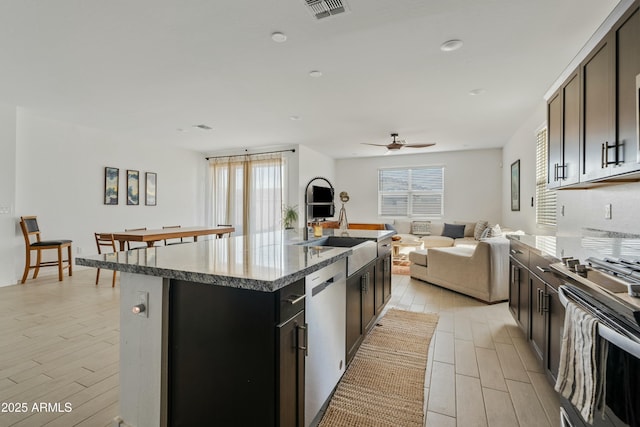 kitchen with stainless steel appliances, an island with sink, and ceiling fan