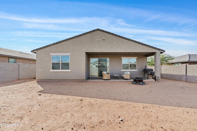 back of property with a fire pit and a patio