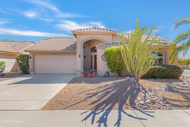 mediterranean / spanish house with stucco siding, an attached garage, a tile roof, and driveway