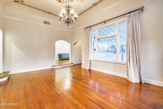 interior space with ornamental molding, wood-type flooring, and an inviting chandelier