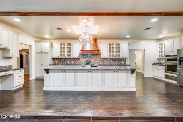 kitchen featuring premium range hood, a center island, dark stone counters, and pendant lighting