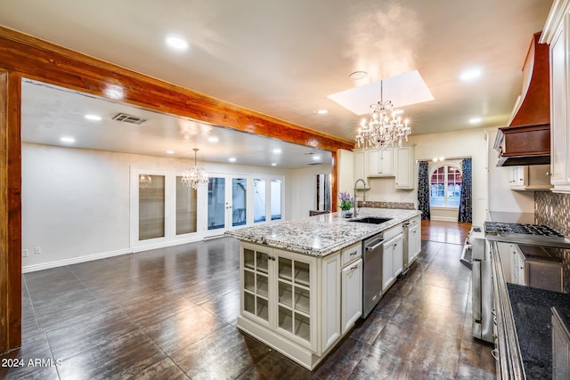 kitchen featuring decorative light fixtures, plenty of natural light, a kitchen island with sink, and sink