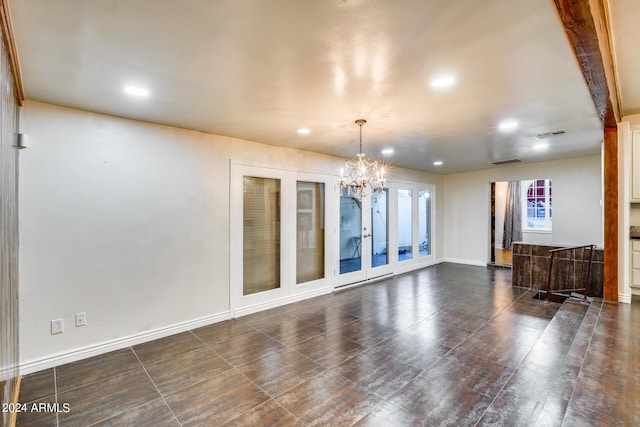 spare room with french doors, an inviting chandelier, and beam ceiling