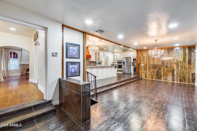 interior space featuring stainless steel refrigerator with ice dispenser, dark wood-type flooring, a notable chandelier, white cabinets, and hanging light fixtures