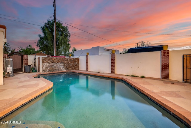 pool at dusk featuring a patio area and gas water heater