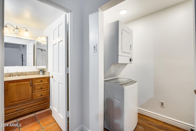 laundry area featuring stacked washer and dryer, light hardwood / wood-style flooring, and sink