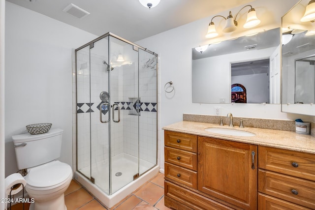 bathroom featuring toilet, vanity, tile patterned floors, and a shower with shower door