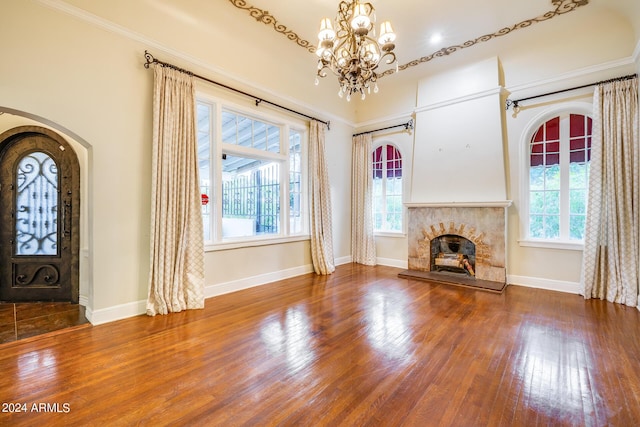 unfurnished living room featuring crown molding, plenty of natural light, a chandelier, and hardwood / wood-style flooring