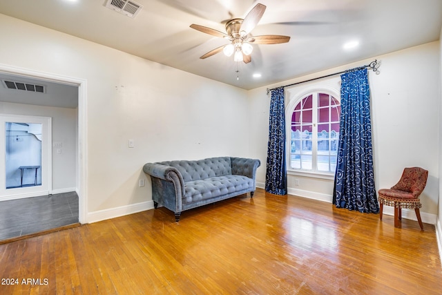 living area with wood-type flooring and ceiling fan