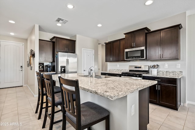 kitchen featuring sink, a breakfast bar area, a kitchen island with sink, stainless steel appliances, and light tile patterned flooring