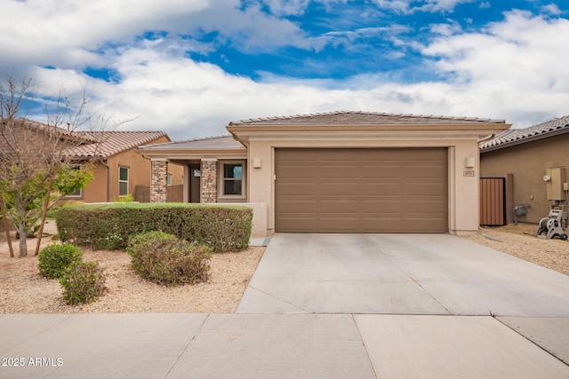 view of front of property with a tile roof, stucco siding, concrete driveway, an attached garage, and stone siding