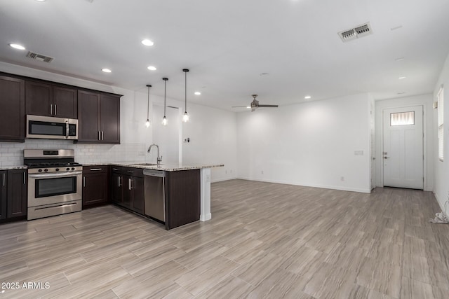 kitchen featuring dark brown cabinetry, visible vents, appliances with stainless steel finishes, a peninsula, and a sink