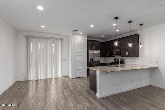 kitchen with dark brown cabinetry, visible vents, a peninsula, stainless steel appliances, and a sink