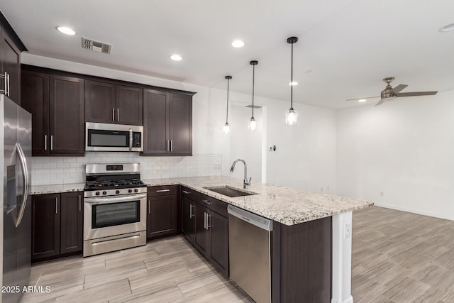 kitchen featuring a peninsula, a sink, visible vents, dark brown cabinets, and appliances with stainless steel finishes