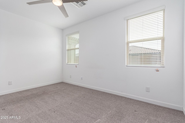 carpeted spare room featuring visible vents, ceiling fan, and baseboards