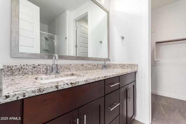 bathroom featuring double vanity, a stall shower, baseboards, and a sink