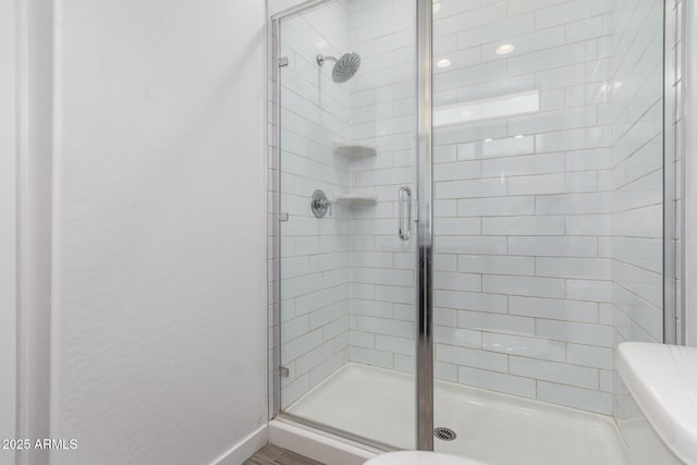 bathroom with a stall shower, baseboards, and toilet