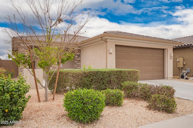 view of front of home featuring a garage, concrete driveway, stone siding, and stucco siding