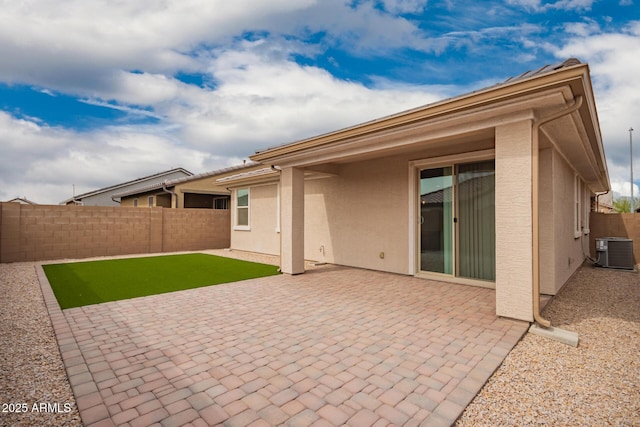 back of property with a fenced backyard, a patio, central AC, and stucco siding