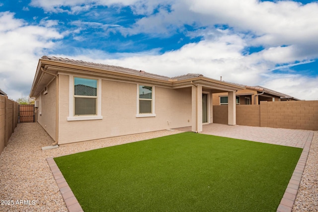 rear view of house featuring a lawn, a patio area, a fenced backyard, and stucco siding