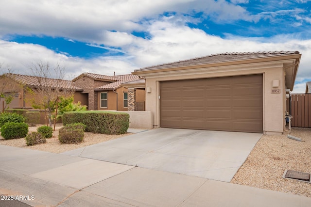 view of front of home with a garage, concrete driveway, a tiled roof, and stucco siding