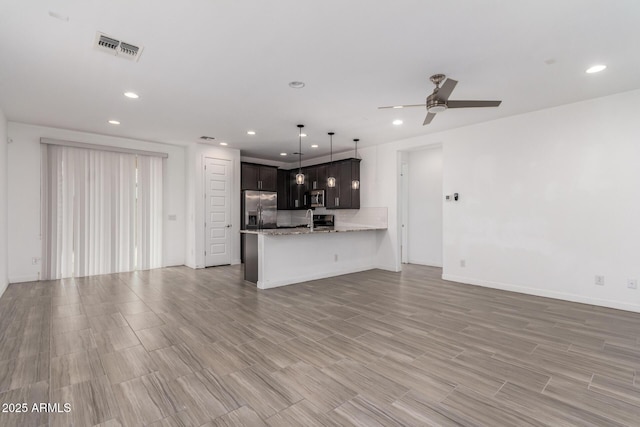 kitchen featuring recessed lighting, a peninsula, a ceiling fan, open floor plan, and appliances with stainless steel finishes