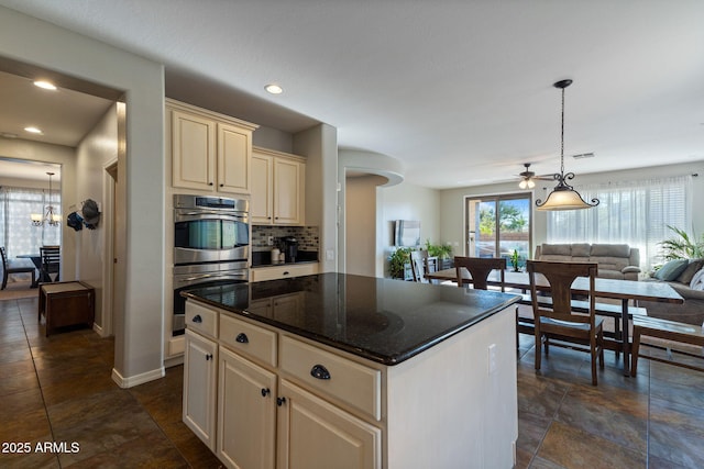 kitchen with cream cabinetry, hanging light fixtures, a center island, double oven, and ceiling fan