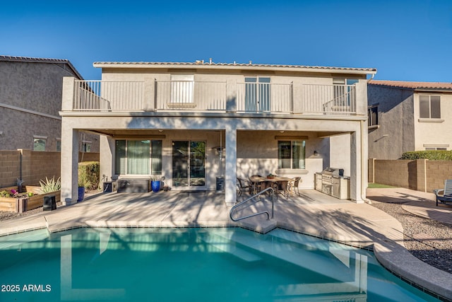 back of house featuring a balcony, a patio area, a fenced in pool, and area for grilling