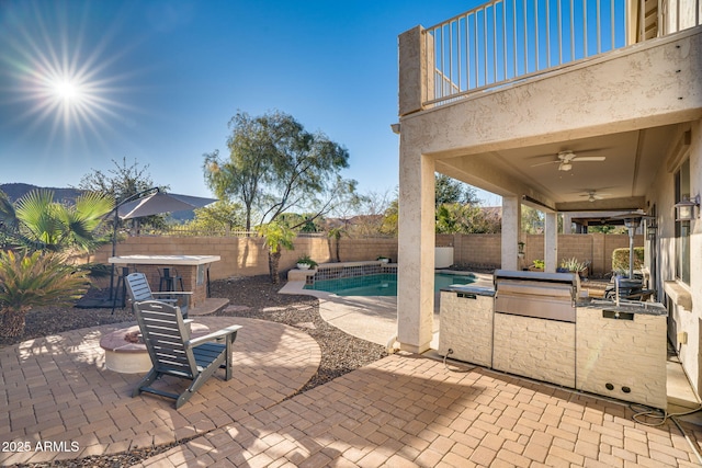 view of patio featuring a fenced in pool, exterior kitchen, ceiling fan, and area for grilling