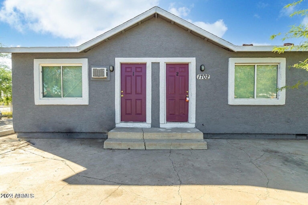 view of front of home with an AC wall unit