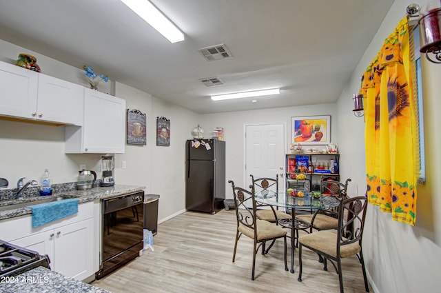 kitchen with light stone countertops, light hardwood / wood-style floors, white cabinetry, and black appliances