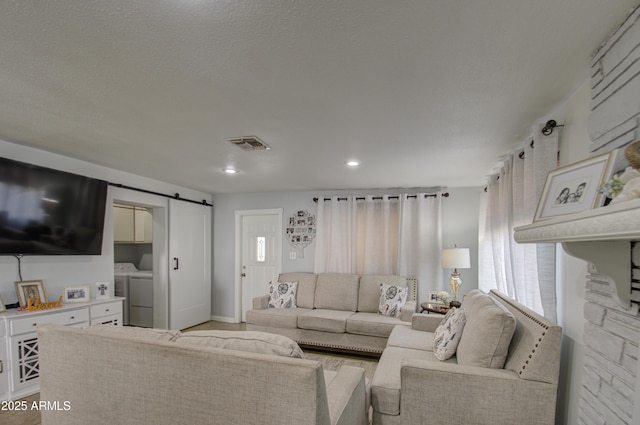 living room with a barn door and washer and clothes dryer