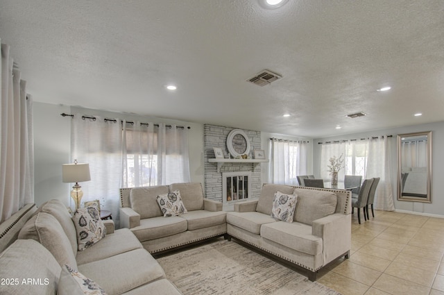 tiled living room with a stone fireplace and a textured ceiling