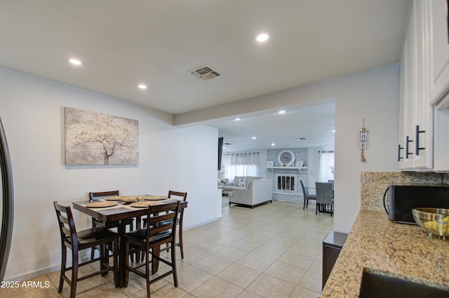 dining space with light tile patterned flooring, sink, and a fireplace