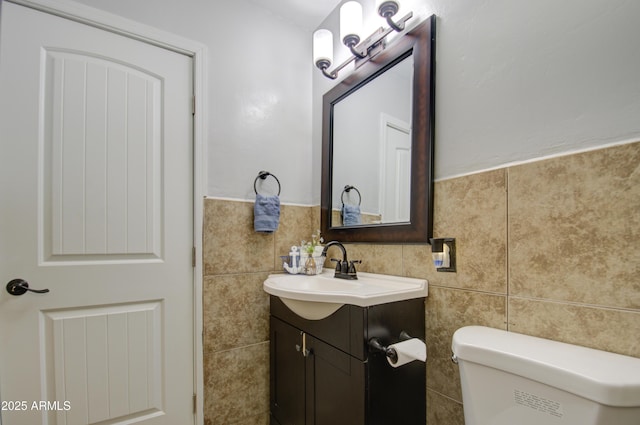 bathroom with vanity, tile walls, and toilet