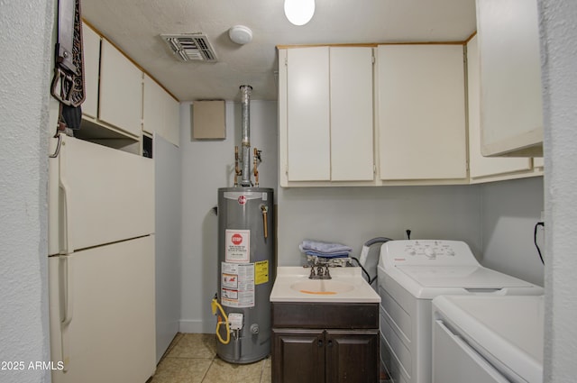 washroom featuring gas water heater, light tile patterned flooring, sink, cabinets, and washing machine and dryer