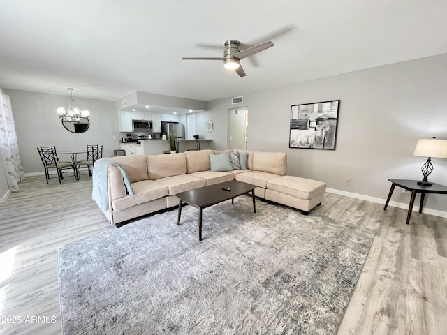 living room featuring light hardwood / wood-style floors and ceiling fan with notable chandelier