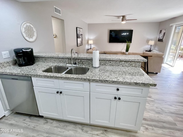 kitchen featuring dishwasher, light stone counters, white cabinetry, and sink