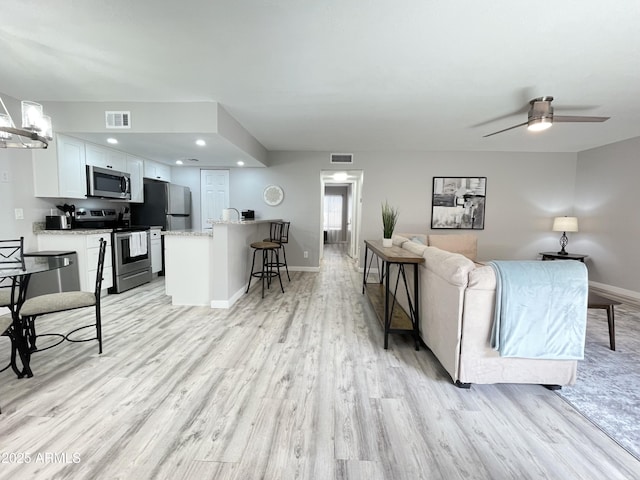 living room with light hardwood / wood-style floors and ceiling fan