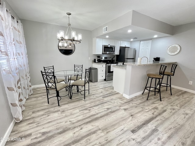 dining room with light wood-type flooring, an inviting chandelier, and sink