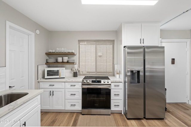 kitchen featuring white cabinetry, appliances with stainless steel finishes, open shelves, and light wood-style flooring