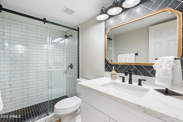 bathroom with toilet, a shower stall, visible vents, and vanity