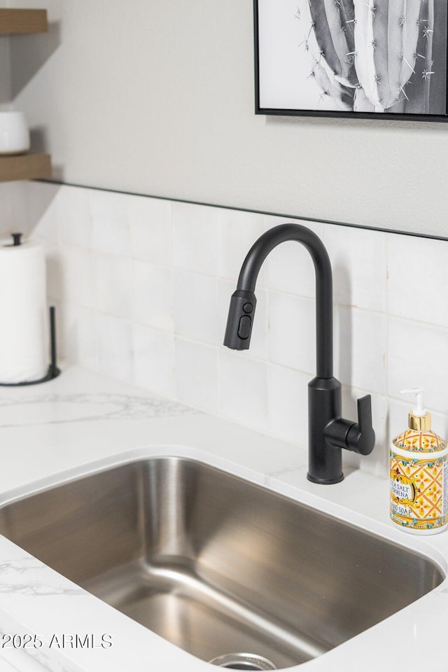 room details with light stone counters, a sink, and decorative backsplash