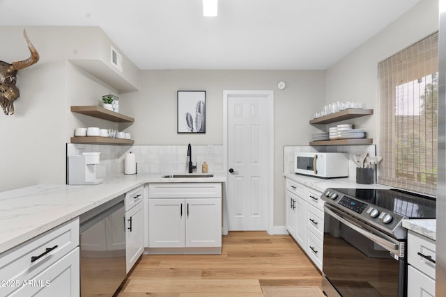 kitchen with stainless steel appliances, a sink, light wood finished floors, and open shelves