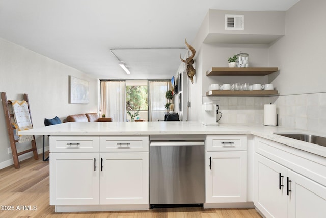 kitchen featuring visible vents, light stone counters, a peninsula, white cabinetry, and stainless steel dishwasher